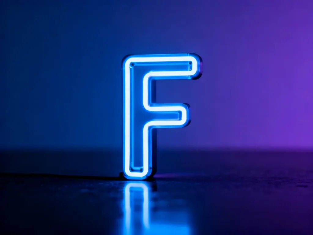 Świecąca neonowa litera „F” na ciemnym, refleksyjnym tle, symbolizująca popularny w internecie zwrot.